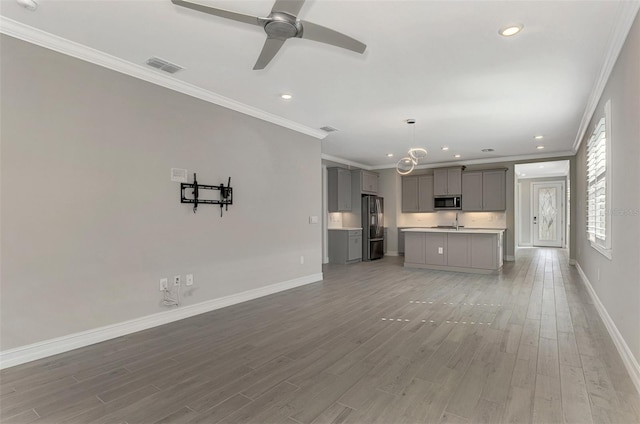 unfurnished living room featuring wood-type flooring, ceiling fan, and crown molding