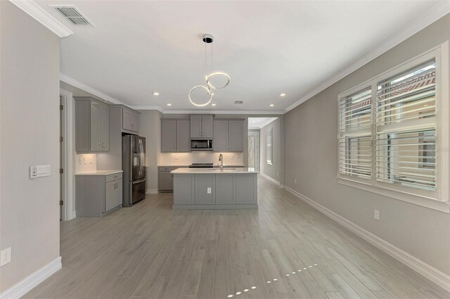 kitchen featuring a kitchen island with sink, hanging light fixtures, light hardwood / wood-style flooring, gray cabinets, and appliances with stainless steel finishes