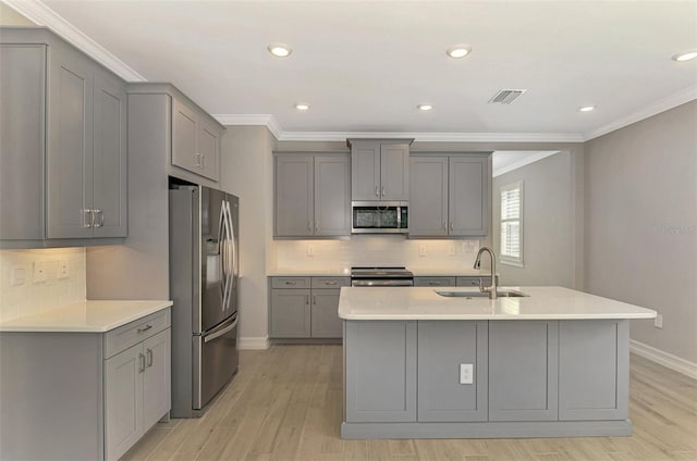 kitchen featuring appliances with stainless steel finishes, light hardwood / wood-style floors, a kitchen island with sink, sink, and gray cabinets