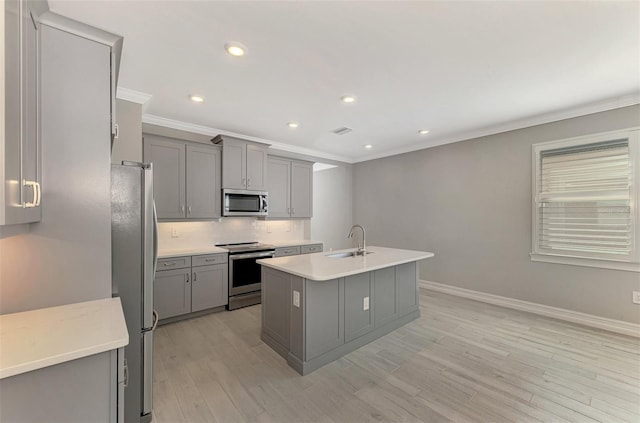 kitchen with gray cabinetry, sink, an island with sink, and stainless steel appliances