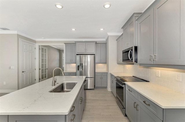 kitchen with sink, light hardwood / wood-style flooring, ornamental molding, and appliances with stainless steel finishes