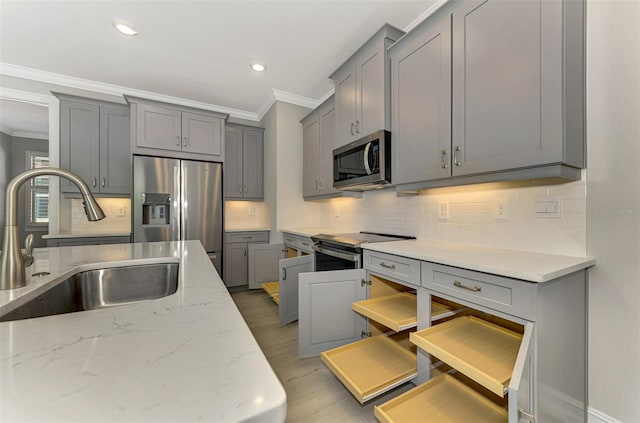 kitchen featuring sink, light wood-type flooring, appliances with stainless steel finishes, tasteful backsplash, and light stone counters