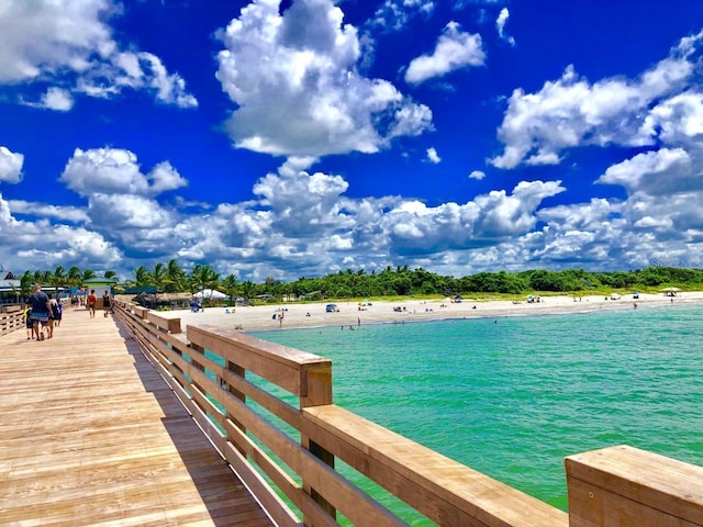 view of dock featuring a beach view and a water view