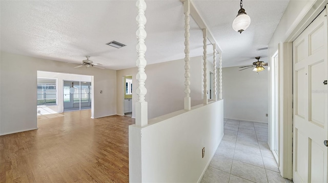 hall with a textured ceiling and light tile patterned flooring