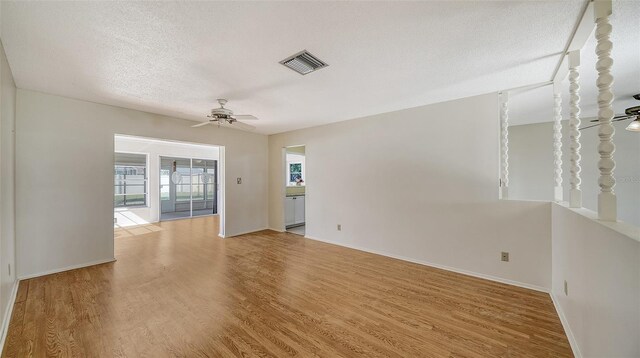 empty room with a textured ceiling, light hardwood / wood-style floors, and ceiling fan