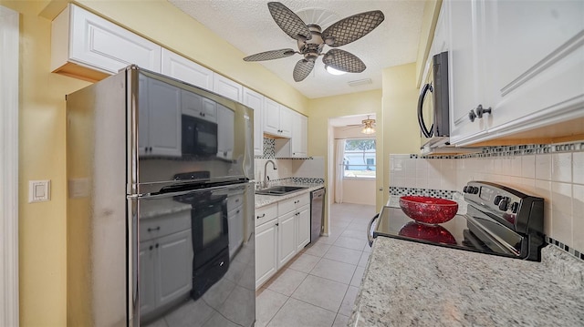 kitchen with light tile patterned flooring, white cabinetry, sink, black appliances, and a textured ceiling