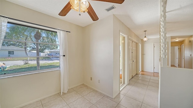 tiled spare room with ceiling fan and a textured ceiling