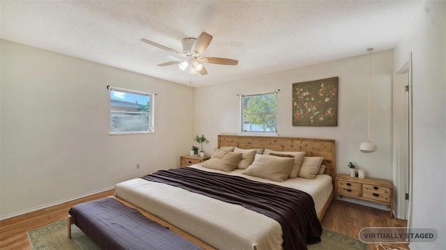 bedroom with hardwood / wood-style flooring, a textured ceiling, and ceiling fan