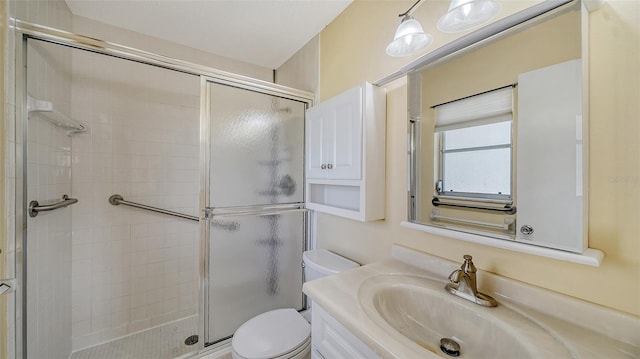 bathroom featuring a shower with door, vanity, and toilet