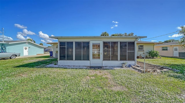 back of house with a sunroom and a lawn