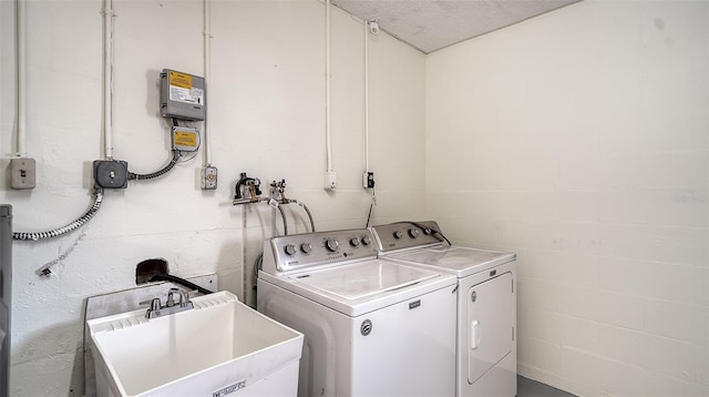 clothes washing area with separate washer and dryer, sink, and a textured ceiling