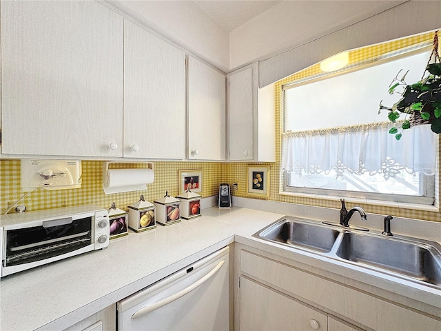 210 Park Blvd N Unit 129, Venice, FL 34285 - kitchen featuring dishwasher, a sink, light countertops, decorative backsplash, and white cabinets