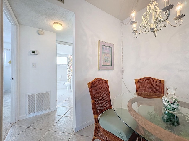 tiled dining area with a chandelier and a textured ceiling