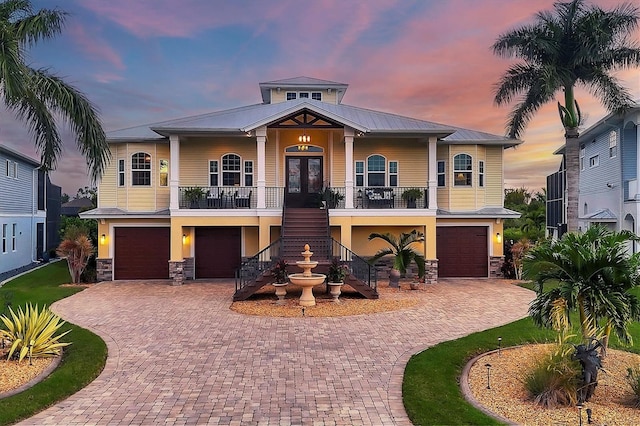 view of front facade with covered porch, a garage, and french doors