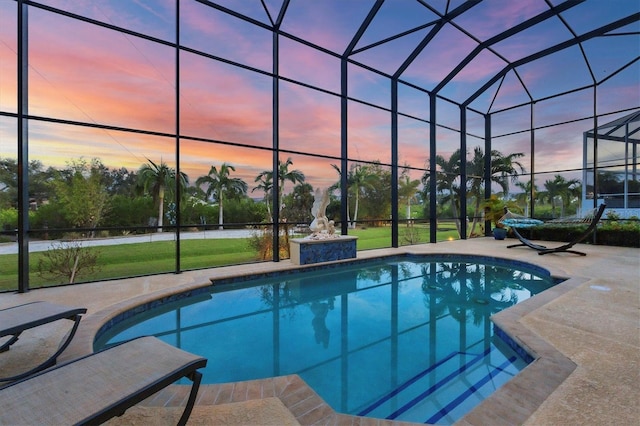 pool at dusk with a lawn, glass enclosure, and a patio