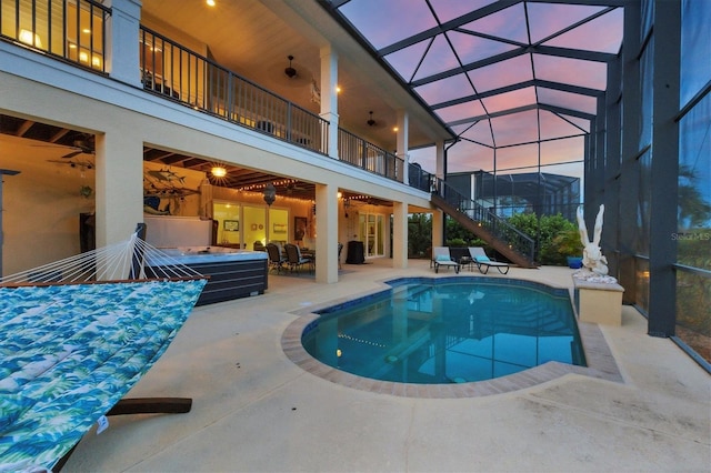 pool at dusk featuring a hot tub, a lanai, and a patio area