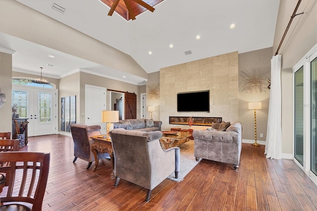 living room with a tile fireplace, ceiling fan, vaulted ceiling, hardwood / wood-style flooring, and ornamental molding