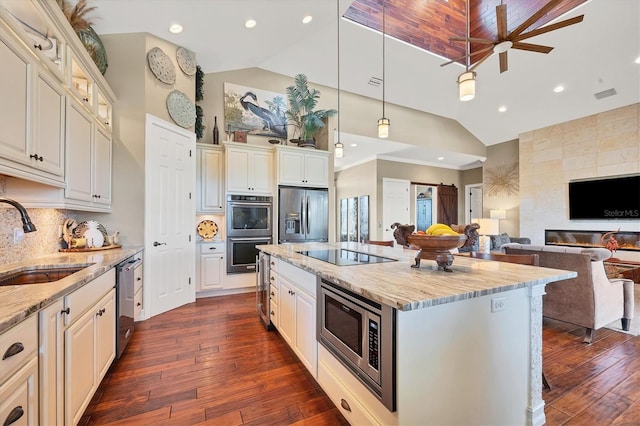 kitchen featuring sink, dark wood-type flooring, light stone counters, decorative backsplash, and appliances with stainless steel finishes