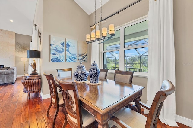 dining area featuring high vaulted ceiling, dark hardwood / wood-style floors, and an inviting chandelier