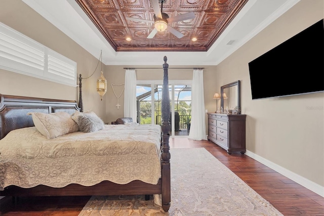 bedroom featuring access to outside, a tray ceiling, ceiling fan, crown molding, and dark wood-type flooring