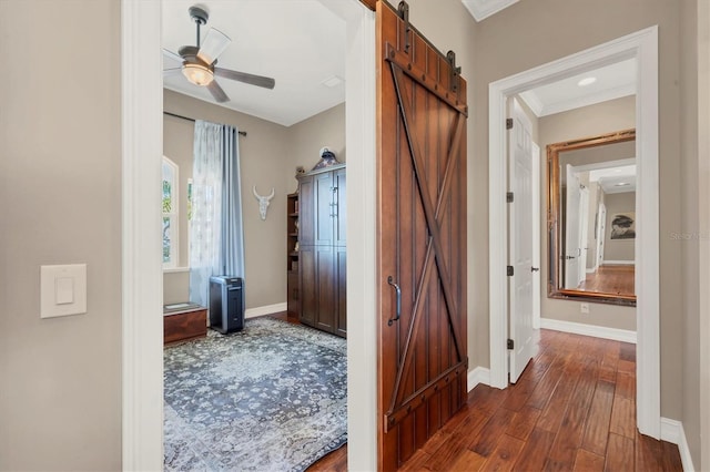 corridor featuring a barn door, dark hardwood / wood-style floors, and ornamental molding