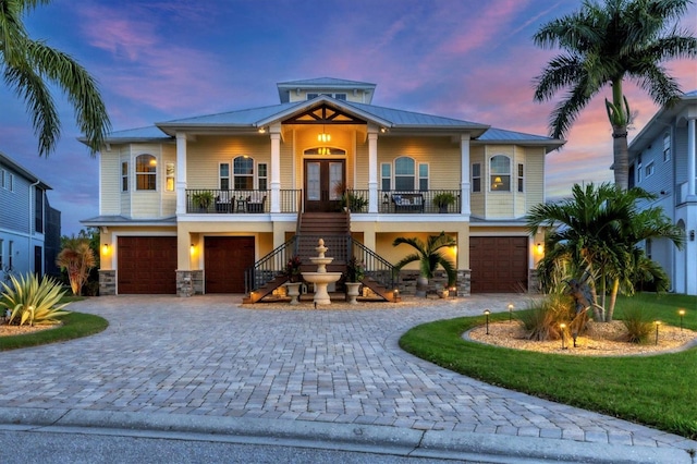 view of front of home with a porch, a garage, and french doors