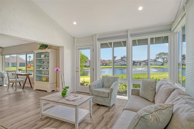 sunroom with a wealth of natural light, a water view, and vaulted ceiling