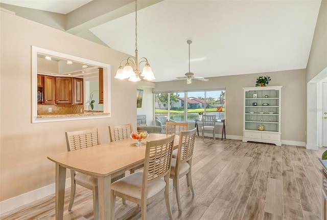 dining room featuring ceiling fan with notable chandelier, vaulted ceiling, and light wood-type flooring