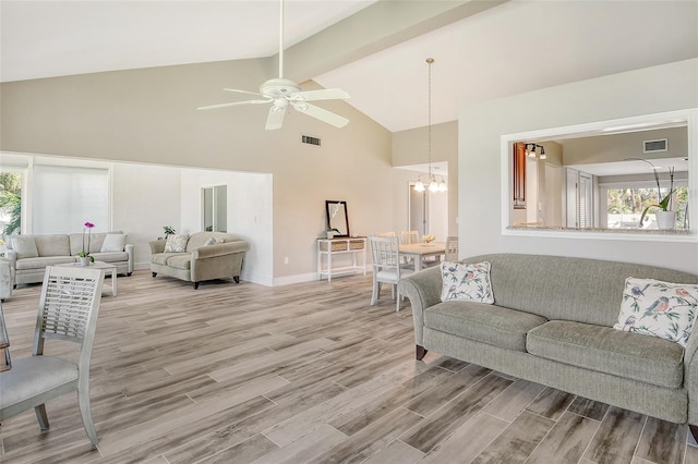 living room featuring beam ceiling, a healthy amount of sunlight, ceiling fan with notable chandelier, and light wood-type flooring