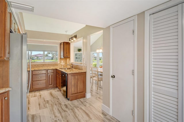 kitchen with sink, light hardwood / wood-style flooring, decorative backsplash, black dishwasher, and stainless steel refrigerator