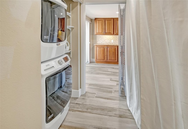 corridor with light hardwood / wood-style floors and stacked washer / dryer