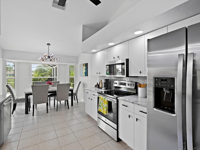 kitchen featuring white cabinetry, light stone counters, a notable chandelier, and appliances with stainless steel finishes