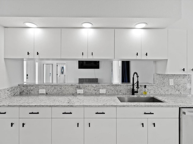 kitchen featuring white cabinets, dishwasher, light stone countertops, and sink