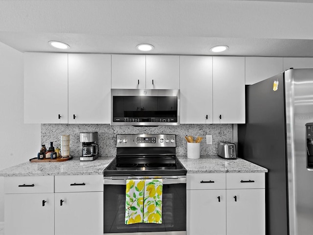 kitchen featuring light stone countertops, decorative backsplash, white cabinets, and stainless steel appliances