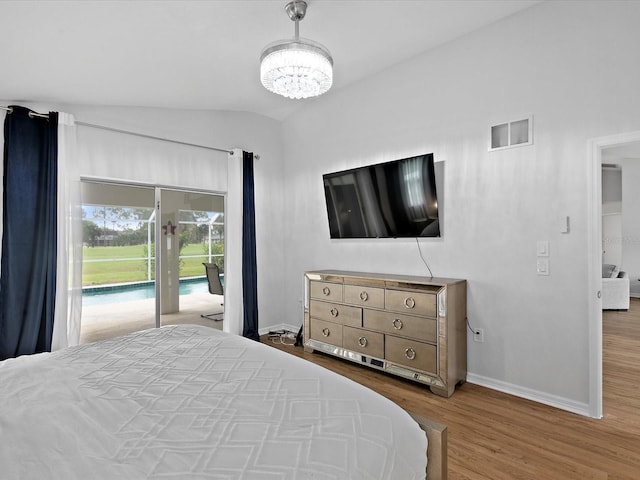 bedroom featuring light hardwood / wood-style floors, access to exterior, lofted ceiling, and an inviting chandelier