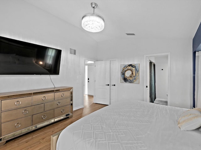 bedroom featuring hardwood / wood-style floors, lofted ceiling, and an inviting chandelier