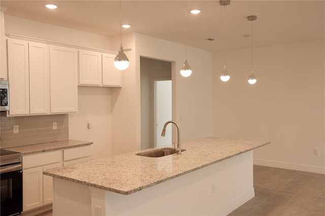 kitchen featuring white cabinets, pendant lighting, a kitchen island with sink, and sink