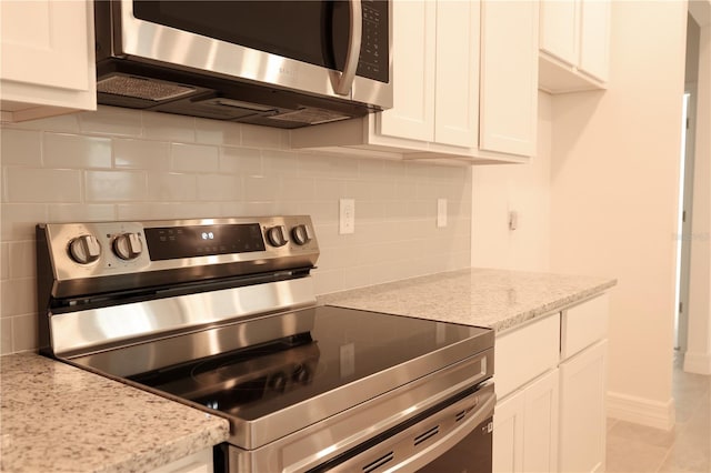 kitchen featuring decorative backsplash, white cabinetry, light stone counters, and appliances with stainless steel finishes