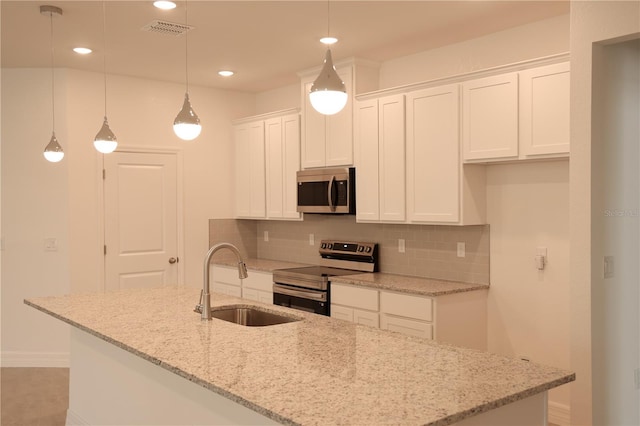 kitchen featuring appliances with stainless steel finishes, sink, decorative light fixtures, a center island with sink, and white cabinetry