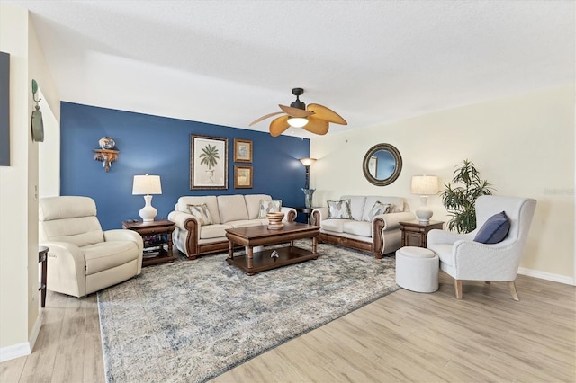 living room featuring ceiling fan, light hardwood / wood-style floors, and a textured ceiling