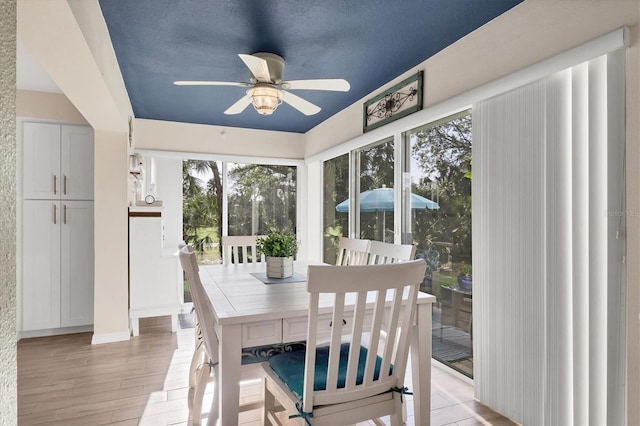 dining area with ceiling fan, light hardwood / wood-style floors, and a textured ceiling