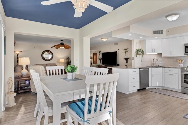 dining space featuring ceiling fan, light wood-type flooring, and sink