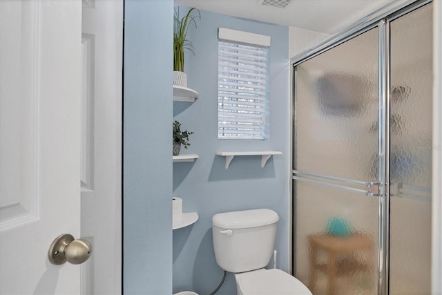 bathroom with toilet and a shower with door