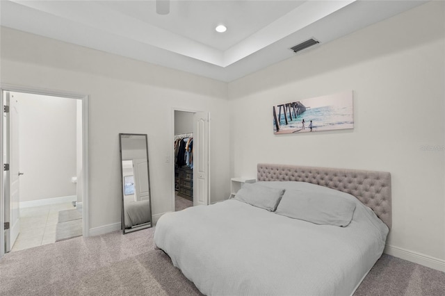 bedroom with light carpet, ensuite bathroom, ceiling fan, a spacious closet, and a closet