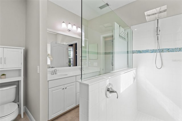 bathroom with toilet, a tile shower, and vanity