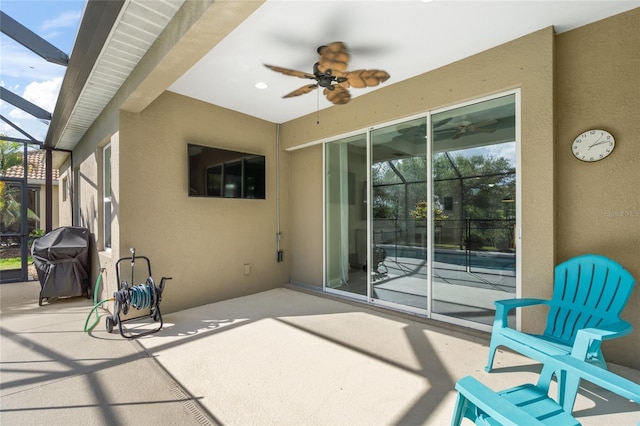 view of patio with a grill, ceiling fan, and glass enclosure