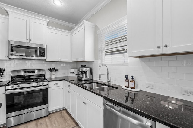 kitchen with appliances with stainless steel finishes, white cabinetry, ornamental molding, and sink