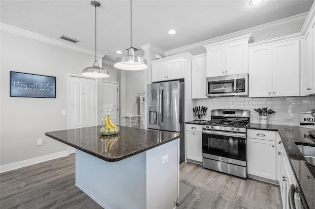 kitchen with pendant lighting, white cabinetry, appliances with stainless steel finishes, and tasteful backsplash