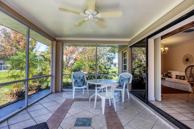 unfurnished sunroom featuring ceiling fan with notable chandelier and a healthy amount of sunlight