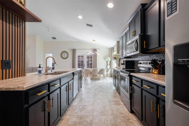 kitchen with lofted ceiling, sink, decorative backsplash, an island with sink, and appliances with stainless steel finishes